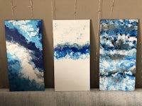 three blue and white paintings on a couch